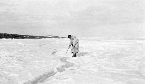 Inuit mother and her baby, trying to hook a fish for supper